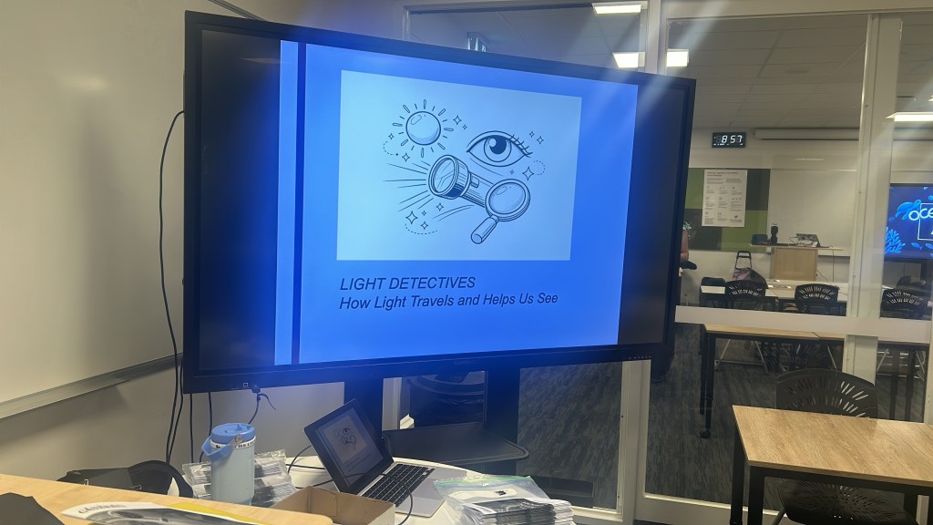 Classroom with Dr Chamali's Coordinate Adventure slide on screen during a Curious Quanta school session