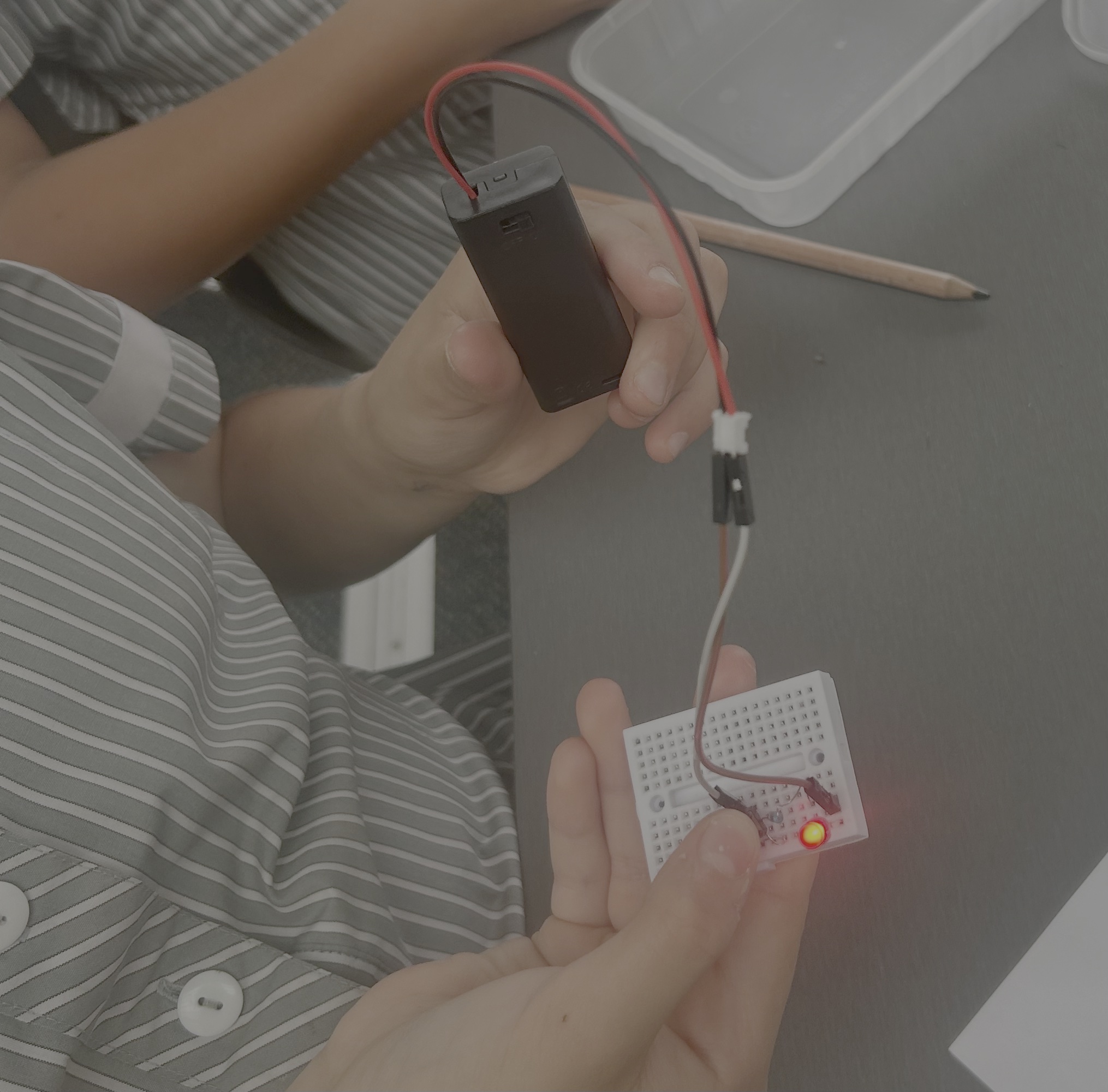 Child holding a breadboard with a glowing red LED during a Circuit Lab STEM workshop