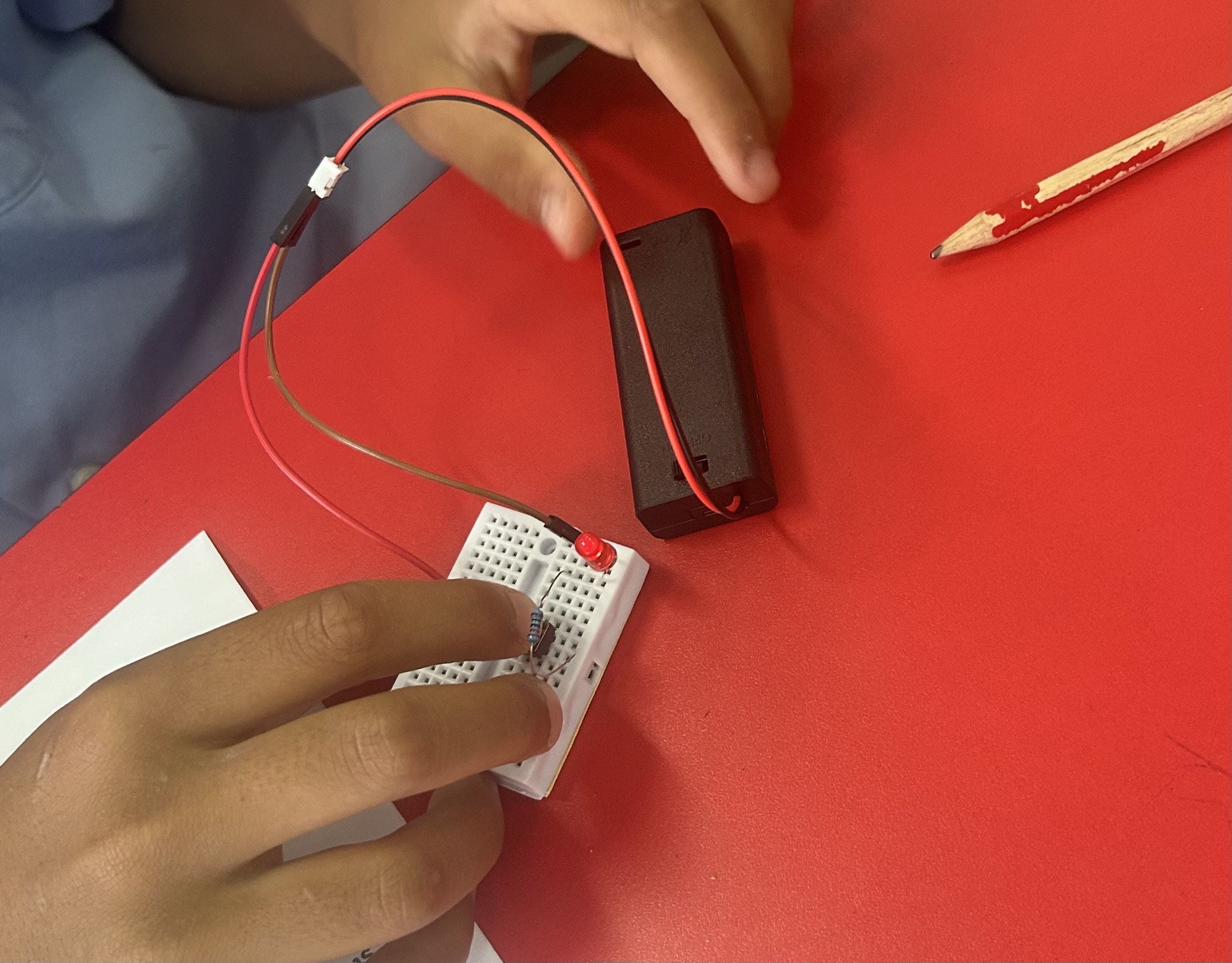 Child pointing at a green LED circuit on a desk during a Smart Circuits Lab workshop