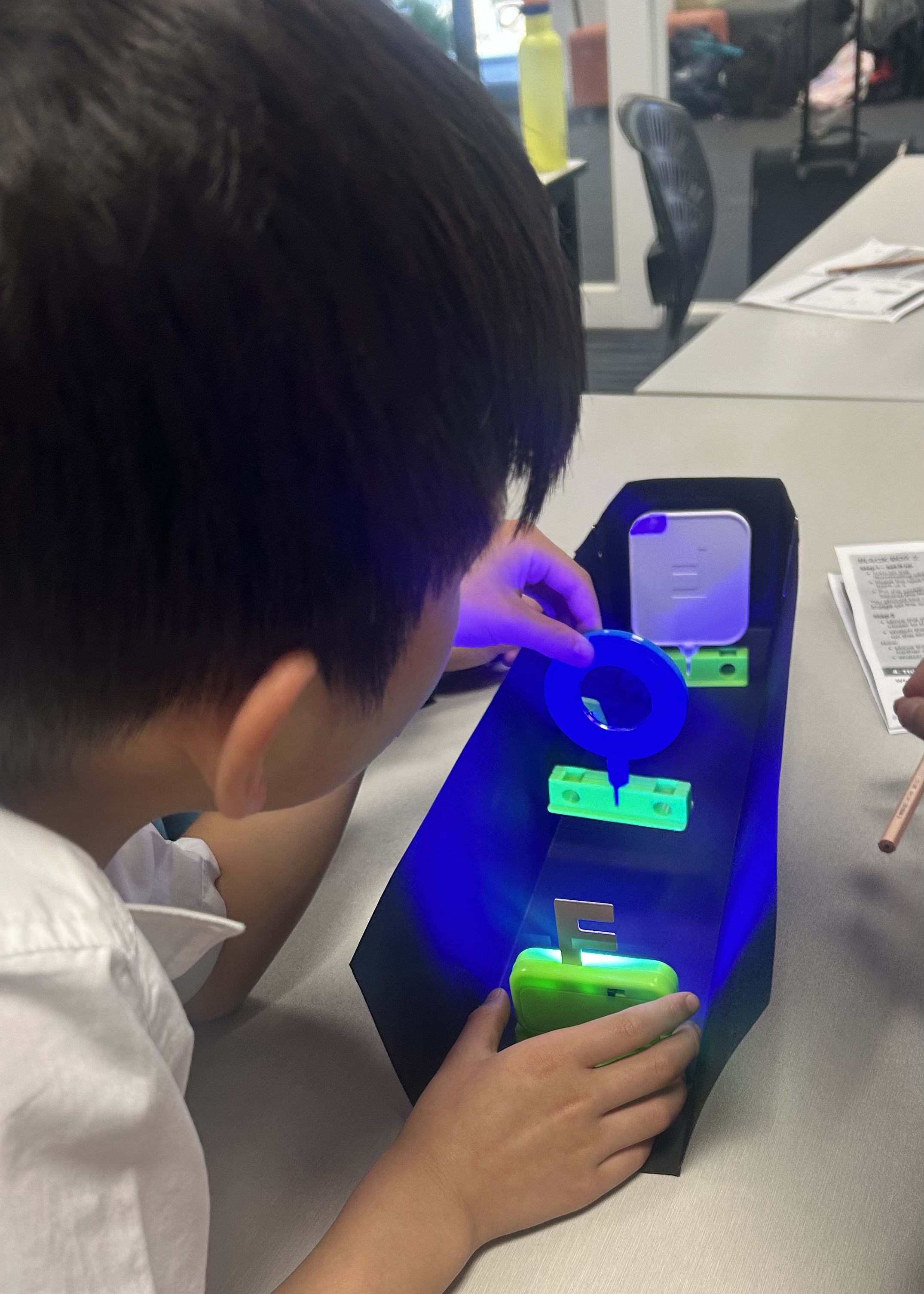 Child looking into an optics and light box during a hands-on STEM workshop