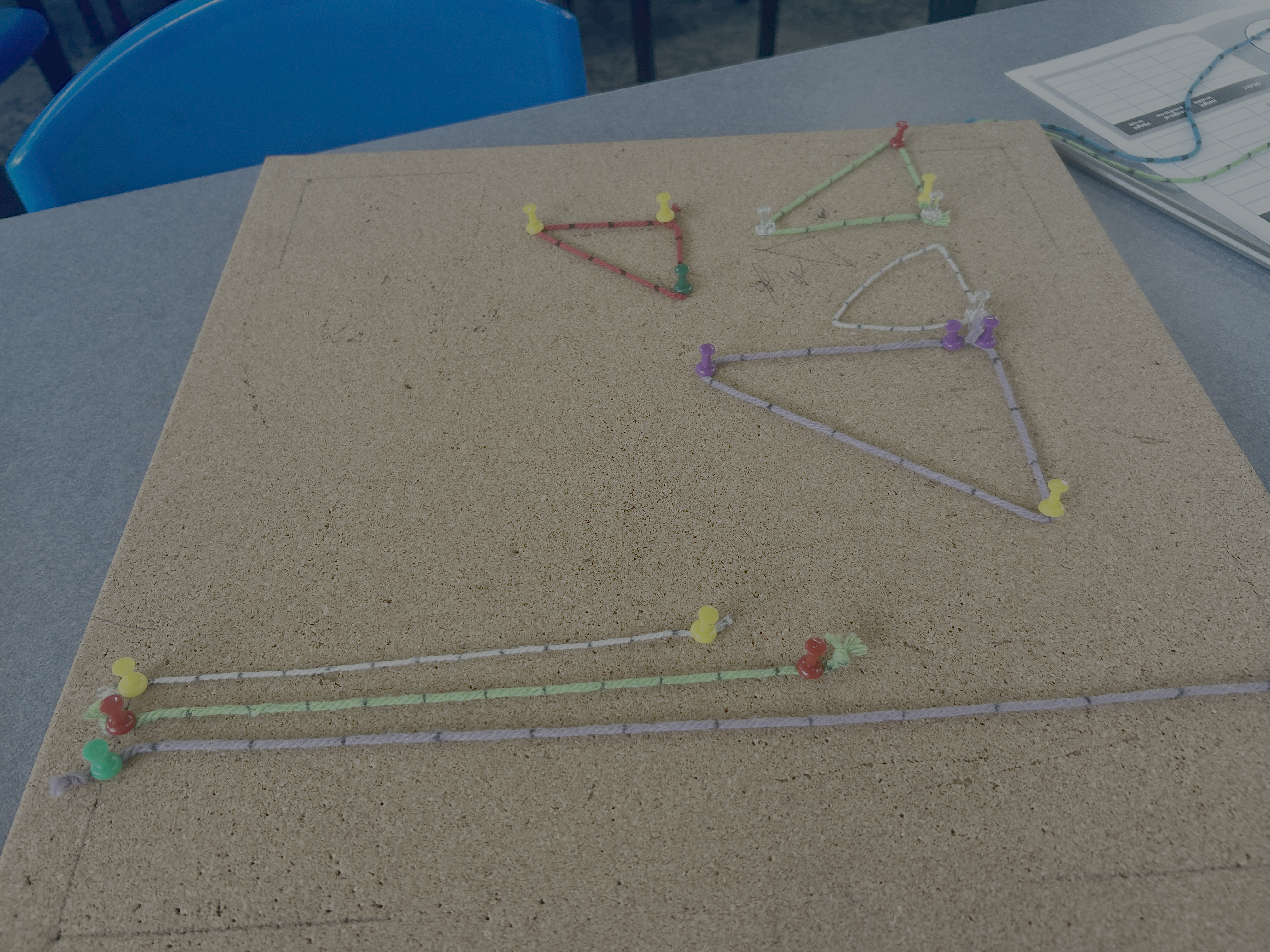 Cork pinboard with coloured string showing geometric patterns during a Coordinate Lab session